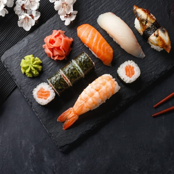 Assorted sushi, including salmon, shrimp, and eel, with wasabi, ginger, and soy sauce.