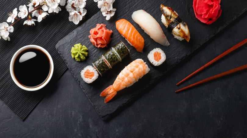 Assorted sushi, including salmon, shrimp, and eel, with wasabi, ginger, and soy sauce.